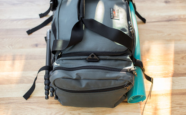 The Road Buddy Lash Straps holding a rolled yoga mat and camera tri-pod on a Road Buddy Duffel 60.